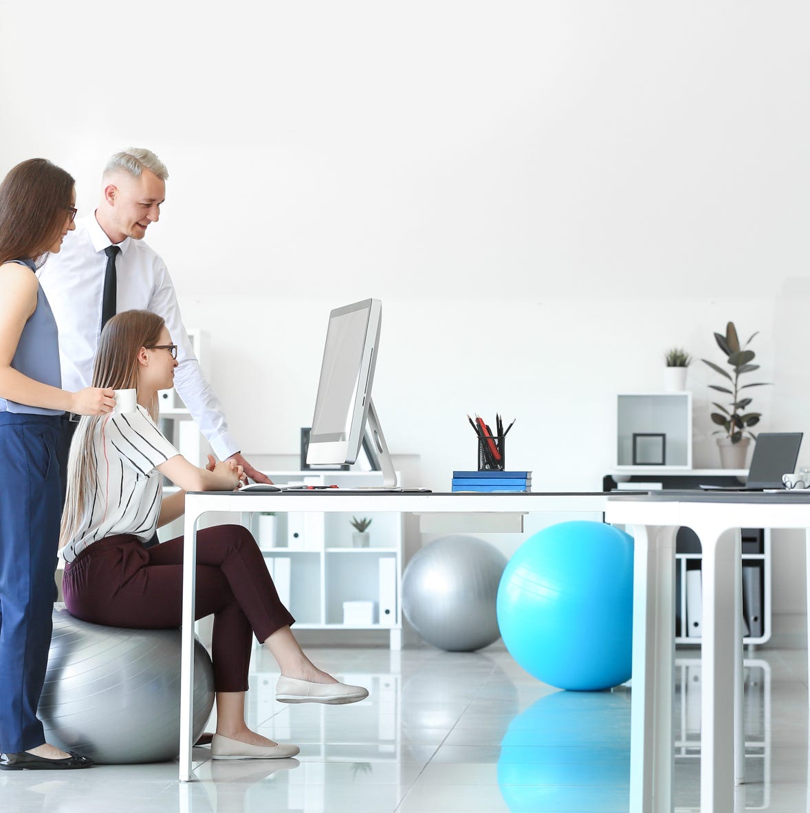 3 Erwachsene besprechen beim Blick auf einen Bildschirm die betriebliche gesundheitsvorsorge-Maßnahmen