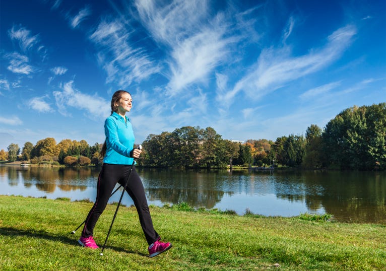 Junge Frau beim Nordic Walking am Fluss